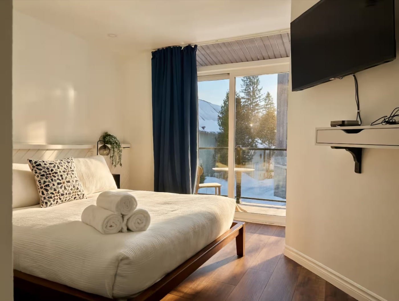 Chambre avec lit double, téléviseur et grande fenêtre sur la nature