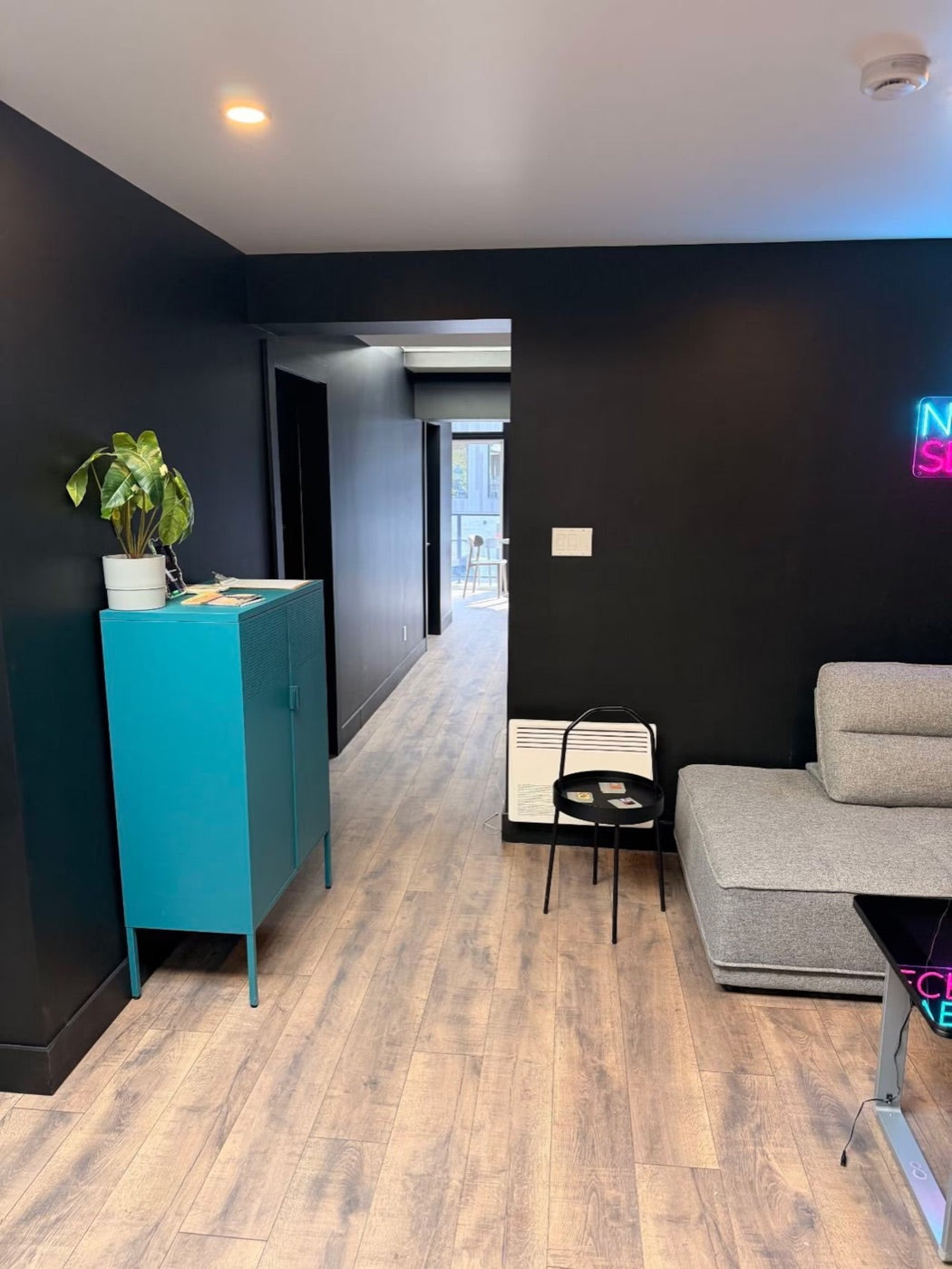 Salon aux murs sombres avec enseigne néon et coin détente